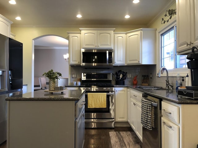 kitchen with appliances with stainless steel finishes, tasteful backsplash, dark stone counters, a center island, and white cabinetry