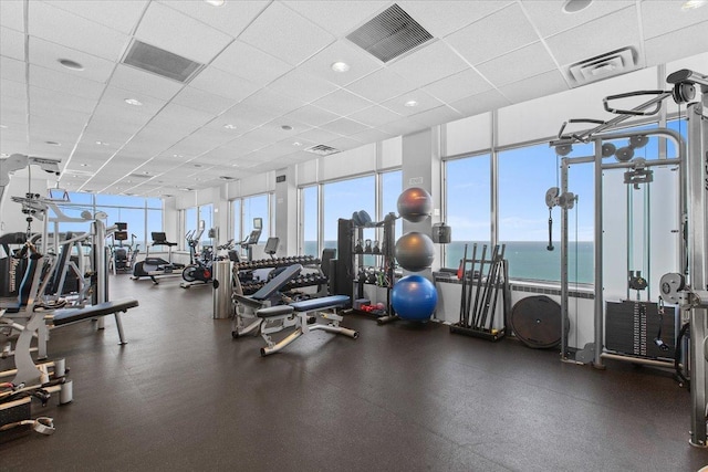 gym featuring a paneled ceiling and a water view