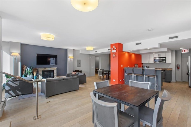 dining space with light hardwood / wood-style floors and a stone fireplace