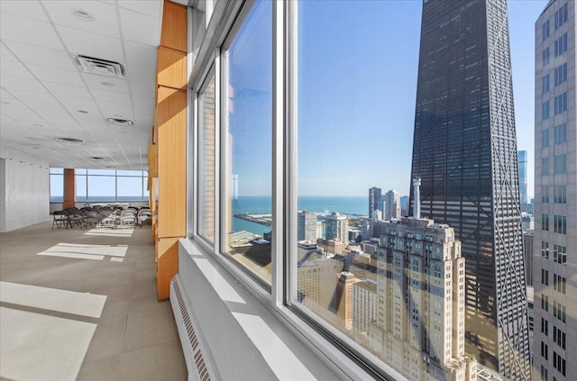 interior space with a paneled ceiling, a healthy amount of sunlight, and a water view