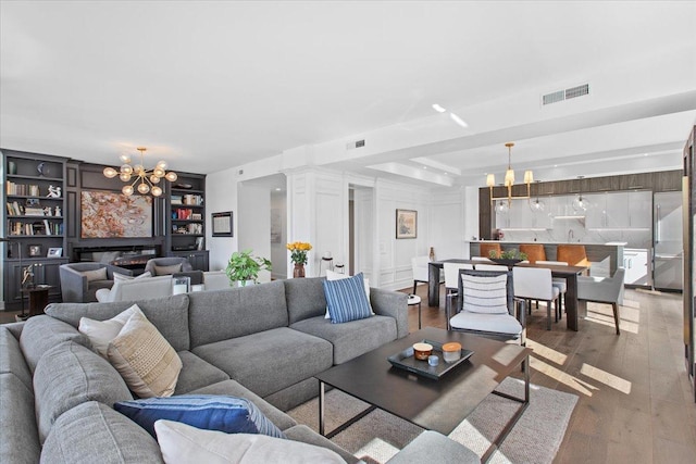 living room featuring hardwood / wood-style floors, built in features, and an inviting chandelier