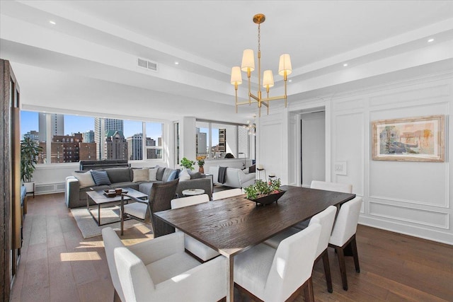 dining space featuring dark hardwood / wood-style flooring, a raised ceiling, and a chandelier