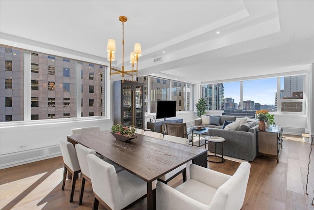 dining room featuring a tray ceiling, an inviting chandelier, and hardwood / wood-style flooring