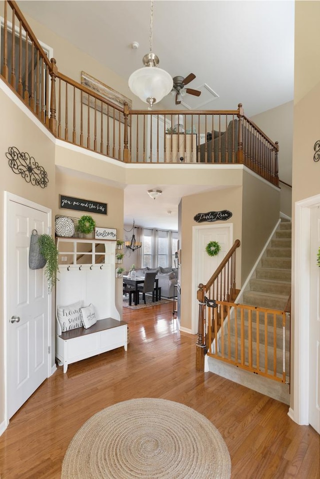 foyer entrance with a high ceiling, ceiling fan, and wood-type flooring