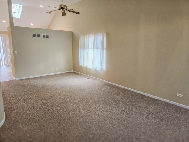 carpeted spare room with ceiling fan, a skylight, and high vaulted ceiling