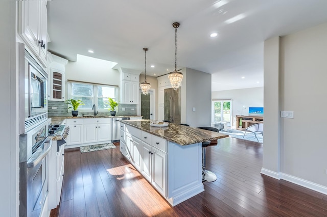 kitchen featuring white cabinets, a center island, tasteful backsplash, and stainless steel appliances