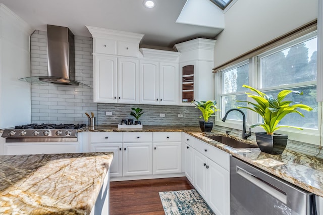 kitchen with wall chimney range hood, sink, light stone counters, white cabinetry, and stainless steel appliances