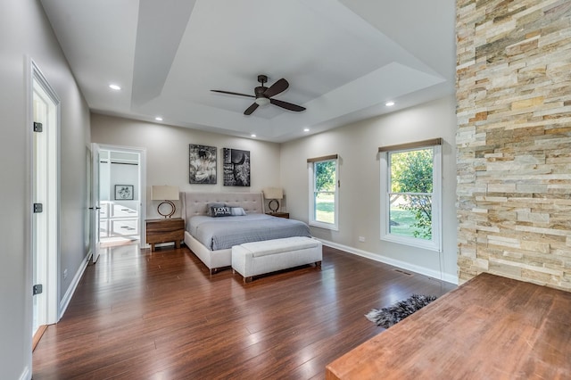 bedroom with dark hardwood / wood-style flooring, a tray ceiling, and ceiling fan