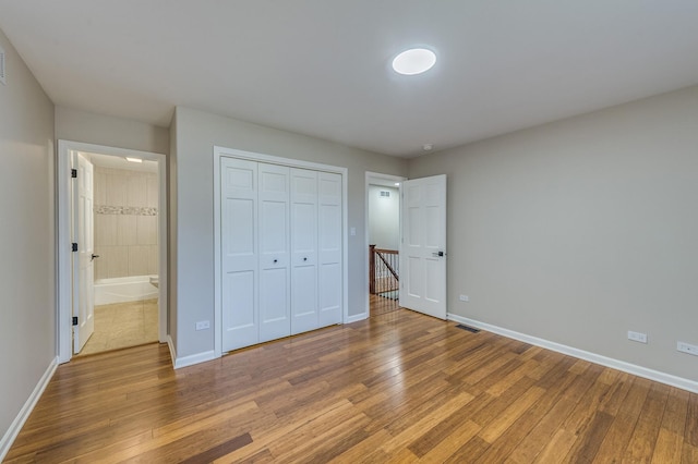 unfurnished bedroom with a closet, light hardwood / wood-style floors, and ensuite bath