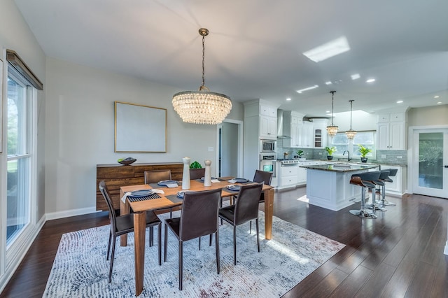 dining room with dark wood-type flooring, a wealth of natural light, a notable chandelier, and sink