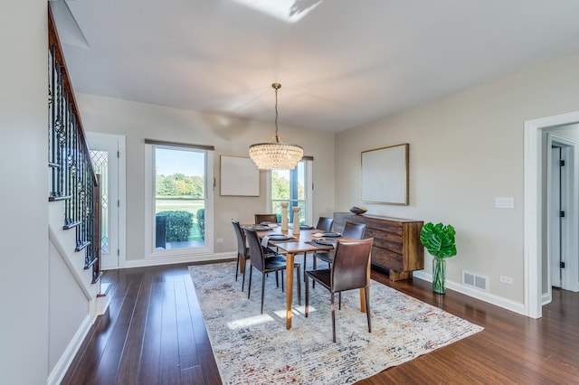 dining space featuring dark wood-type flooring and a notable chandelier