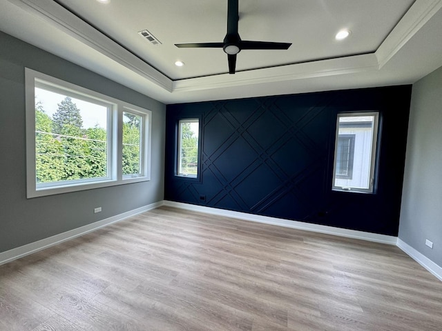 unfurnished room with a raised ceiling, ceiling fan, and light hardwood / wood-style floors