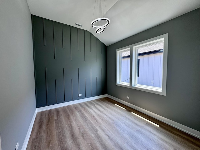 empty room featuring light hardwood / wood-style floors and vaulted ceiling