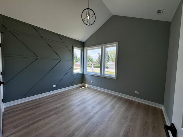 spare room with hardwood / wood-style floors and vaulted ceiling