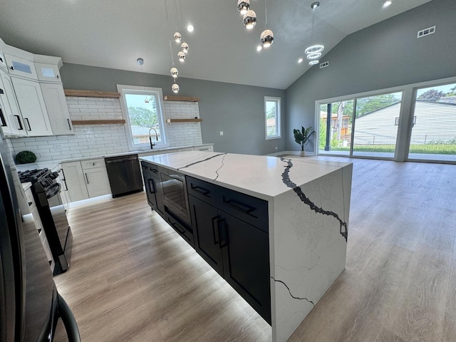 kitchen featuring white cabinetry, a center island, hanging light fixtures, black dishwasher, and decorative backsplash