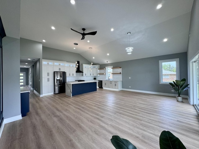 unfurnished living room with ceiling fan, lofted ceiling, and light hardwood / wood-style flooring