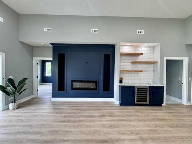 unfurnished living room with light hardwood / wood-style floors and beverage cooler