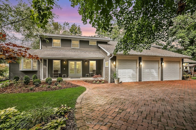 view of front of house with a garage, covered porch, and a lawn