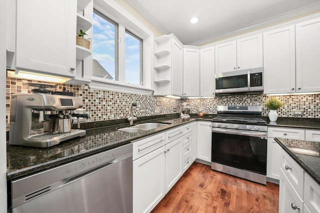 kitchen with sink, tasteful backsplash, dark stone counters, white cabinets, and appliances with stainless steel finishes