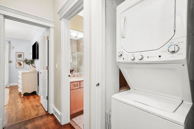 laundry area featuring dark hardwood / wood-style floors, stacked washer / drying machine, and sink