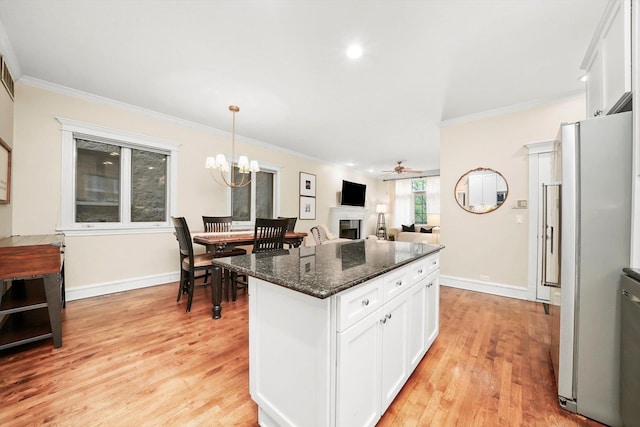 kitchen featuring pendant lighting, ceiling fan with notable chandelier, refrigerator, dark stone countertops, and white cabinetry