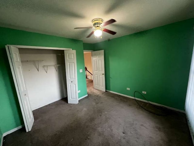 unfurnished bedroom featuring dark colored carpet, a textured ceiling, a closet, and ceiling fan