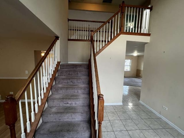 stairs featuring tile patterned flooring and a towering ceiling