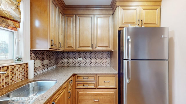 kitchen featuring decorative backsplash, sink, and stainless steel refrigerator