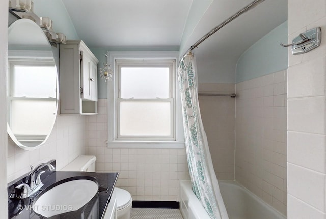 full bathroom with a healthy amount of sunlight, toilet, shower / bath combo with shower curtain, and tile walls