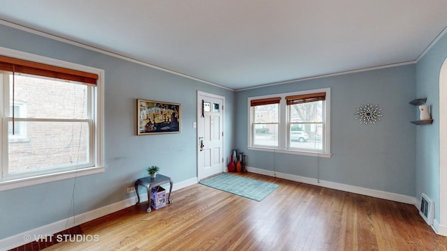 foyer entrance with crown molding, plenty of natural light, and light hardwood / wood-style floors