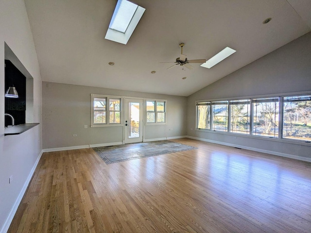 unfurnished living room featuring ceiling fan, a healthy amount of sunlight, vaulted ceiling, and light hardwood / wood-style flooring