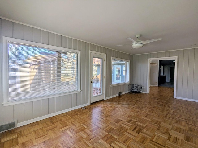 spare room with plenty of natural light, ceiling fan, and light parquet floors