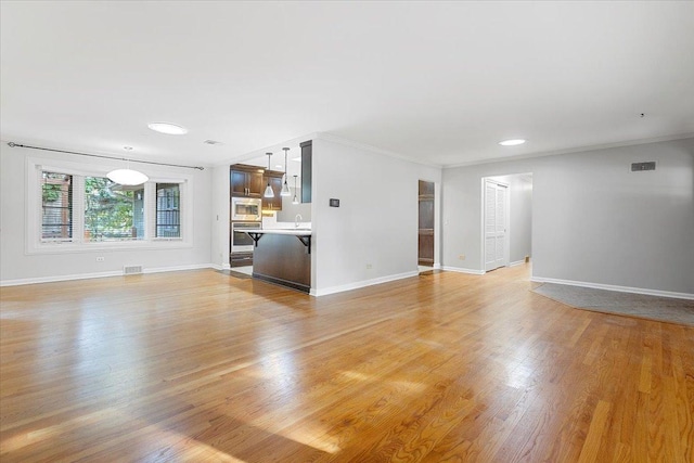 unfurnished living room with crown molding, sink, and light wood-type flooring