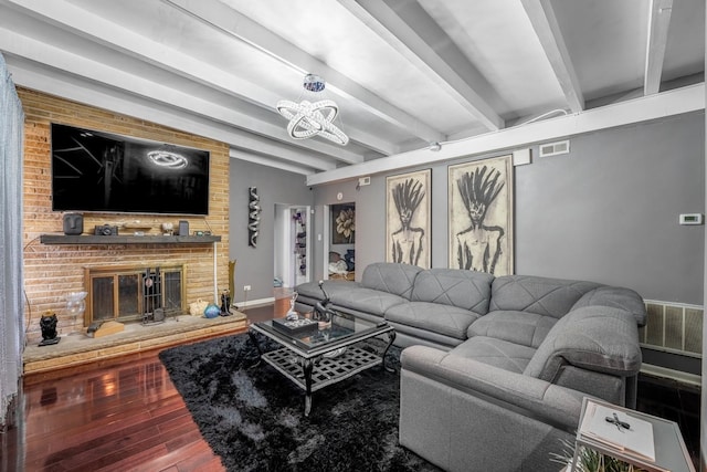 living room with a fireplace, beamed ceiling, an inviting chandelier, and hardwood / wood-style flooring