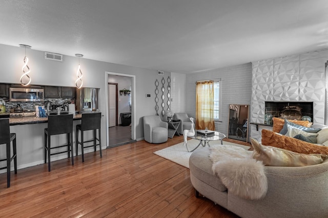 living room with a large fireplace and light hardwood / wood-style flooring