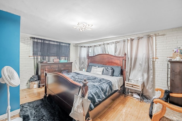 bedroom with hardwood / wood-style floors and brick wall