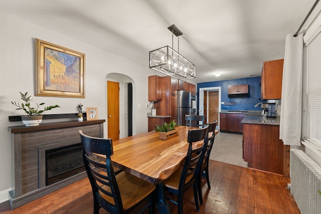 dining space with hardwood / wood-style floors, radiator, and a notable chandelier