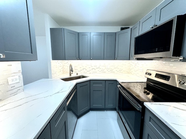 kitchen with backsplash, light stone countertops, sink, and appliances with stainless steel finishes