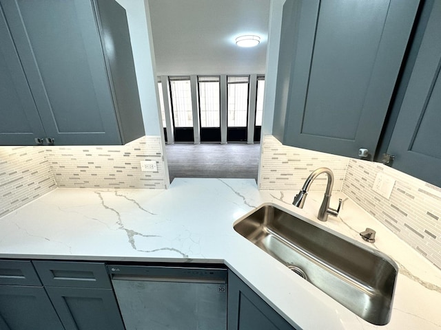 kitchen featuring dishwasher, light stone counters, decorative backsplash, and sink