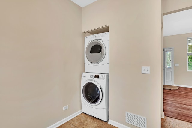 washroom featuring light tile patterned flooring and stacked washer and clothes dryer