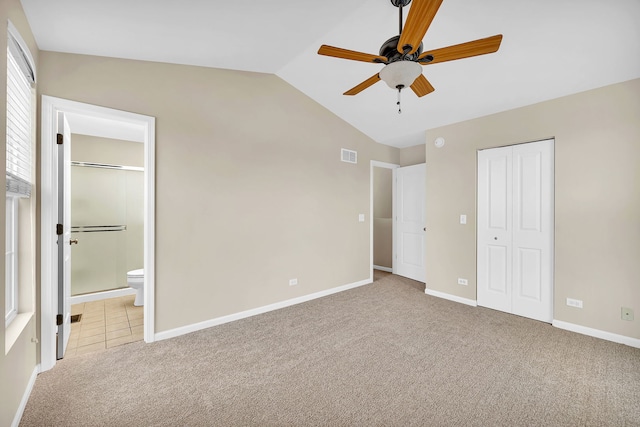 unfurnished bedroom with ensuite bath, ceiling fan, vaulted ceiling, light carpet, and a closet