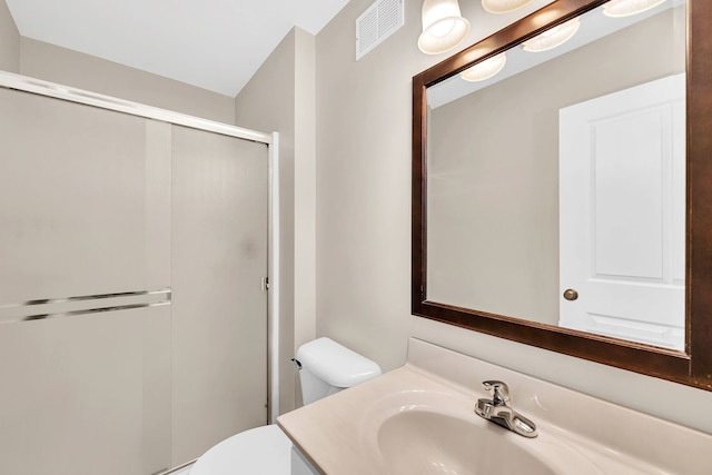 bathroom with vanity, toilet, and a shower with door