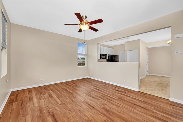 empty room with ceiling fan and light hardwood / wood-style flooring