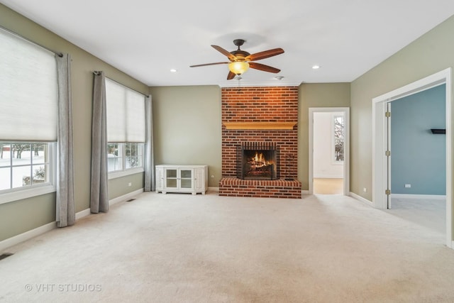 unfurnished living room with ceiling fan, a fireplace, and light colored carpet