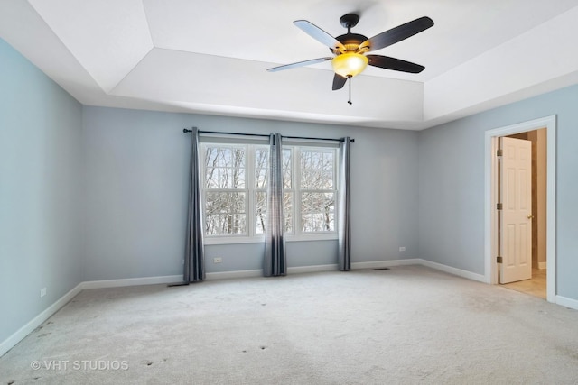 spare room with a tray ceiling, ceiling fan, and light colored carpet