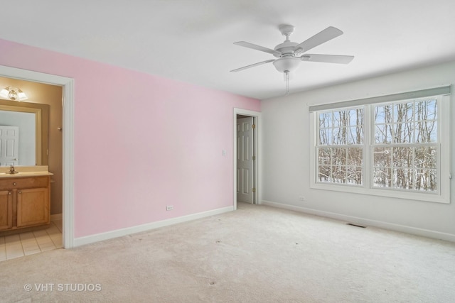 unfurnished bedroom featuring ceiling fan, light colored carpet, sink, and ensuite bath