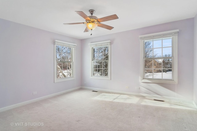 spare room featuring a wealth of natural light, ceiling fan, and light colored carpet