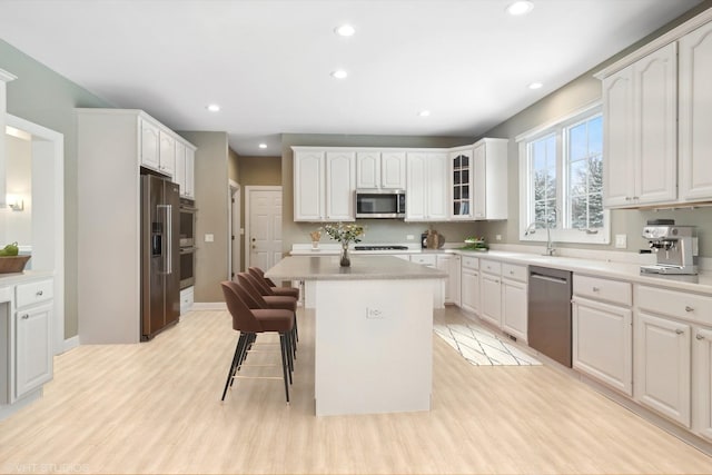 kitchen with a kitchen bar, white cabinets, a kitchen island, and stainless steel appliances