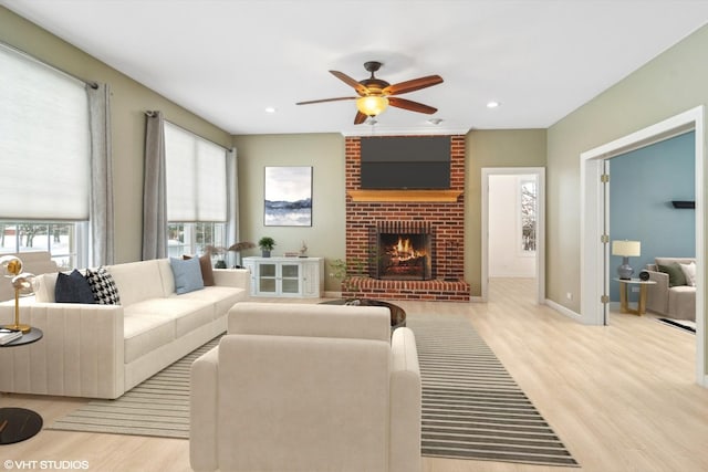 living room with ceiling fan, light wood-type flooring, and a fireplace