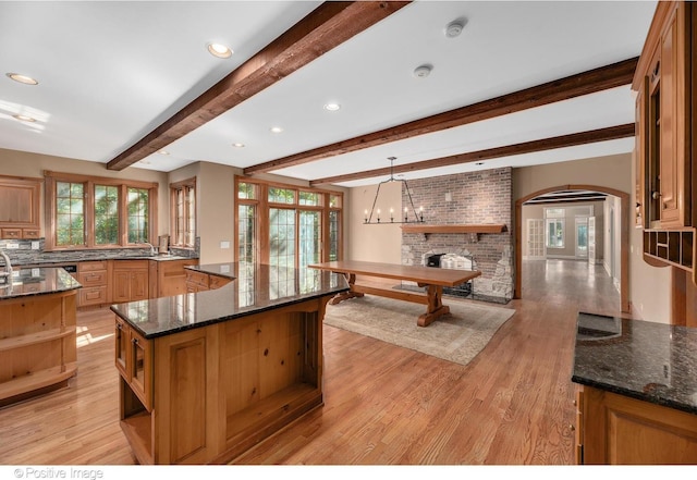 kitchen featuring pendant lighting, a center island, dark stone countertops, and beam ceiling